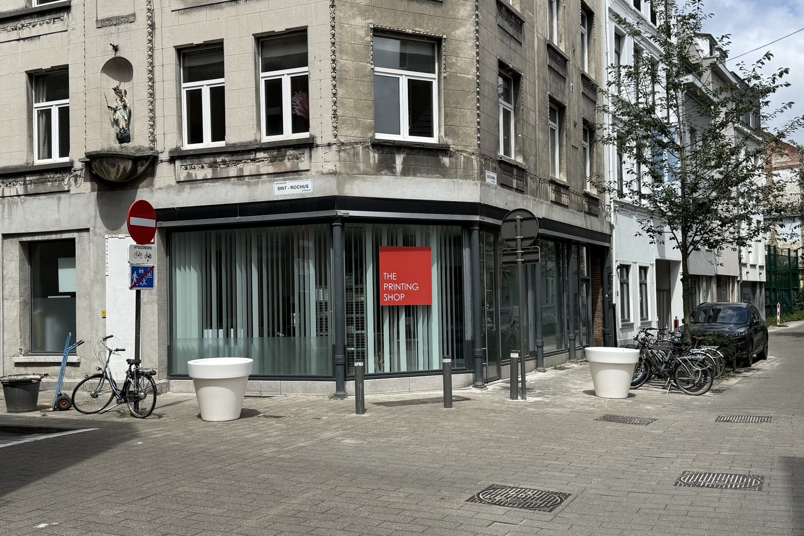 De winkel van The Printing Shop op een straathoek, met het rode logo in het raam